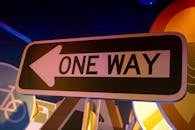 A brightly lit one way street sign with an arrow, captured indoors at night.